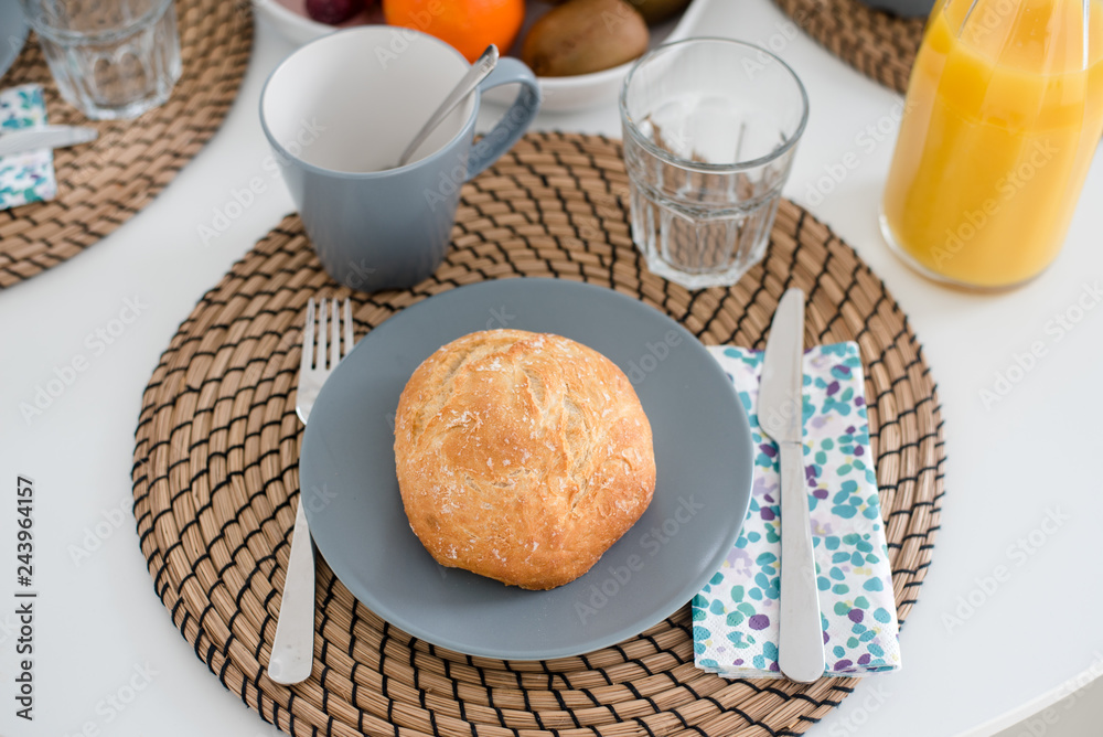 Plate with fresh crusty bread and glass of juice on grey plate