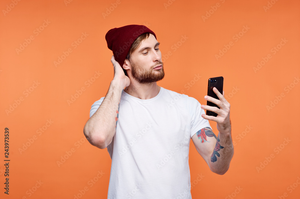man cap looks into the phone against orange background man cap looks into the phone against orange background