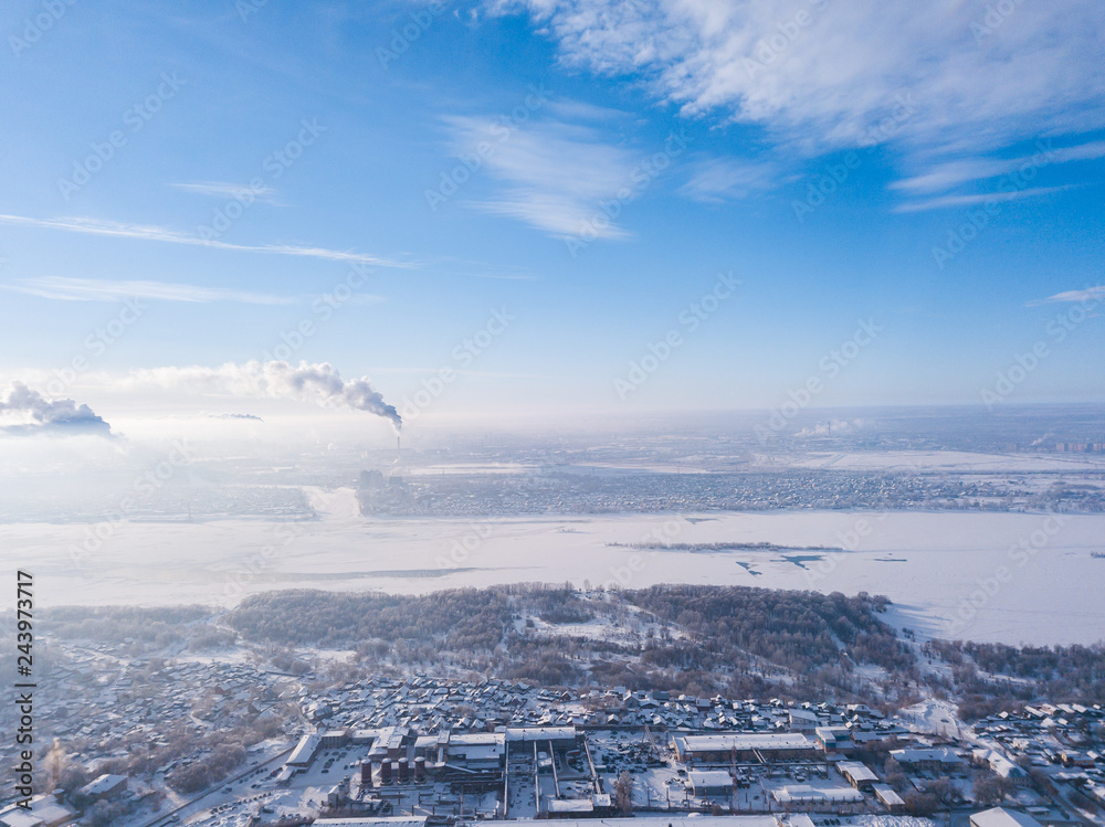 Helicopter drone shot. Aerial photography of a  river with bridge, modern city over an area, a large crossroads, high-rise buildings and cars in winter day