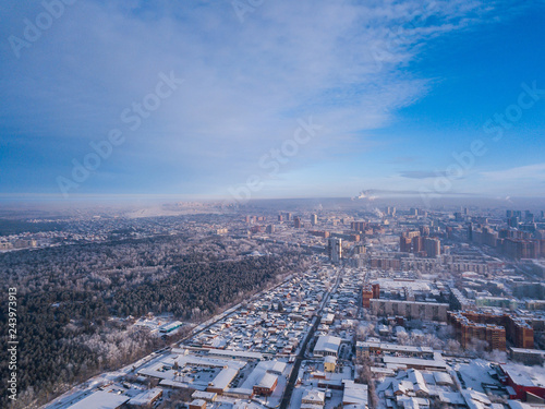 Aerial photography of a modern city: high-rise buildings, a big road, shops and parks on a cold winter day with a blue sky.Helicopter drone shot
