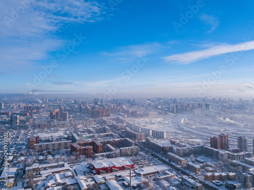 Aerial photography of a modern city: high-rise buildings, a big road, shops and parks on a cold  winter day with a blue sky.Helicopter drone shot © Виталий Сова