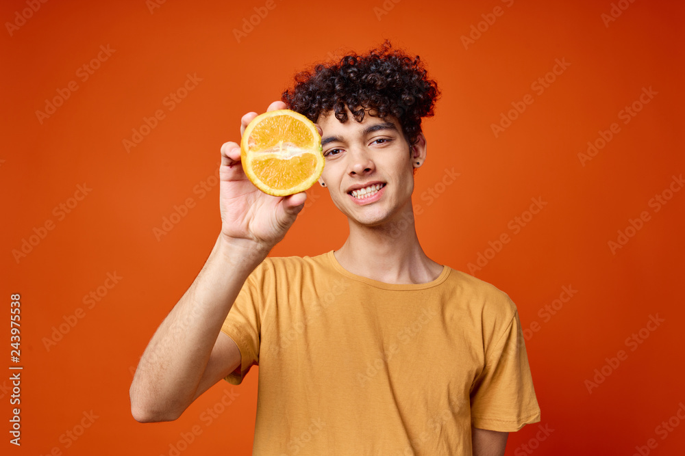 man with curls holds an orange man with curls holds an orange