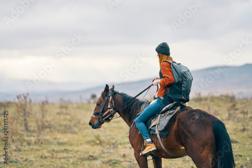 woman with a backpack riding a horse