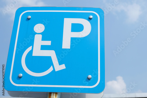 Slope way sign for wheelchair people on blue sky background - Handicapped parking.