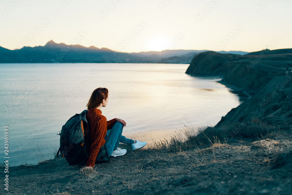 woman sits on a cliff looks at the sea sky evening nature silence