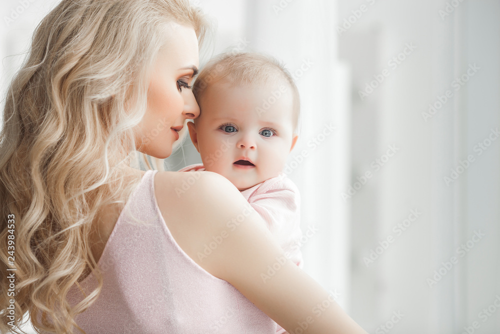 Young pretty mother with her little baby at home. Mom and daughter indoors. month child with her parent in the bedroom. Young pretty mother with her little baby at home. Mom and daughter indoors. month child with her parent in the bedroom.