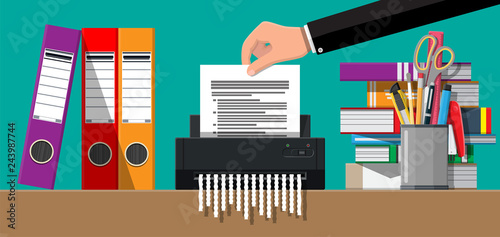 Hand putting document paper in shredder machine.