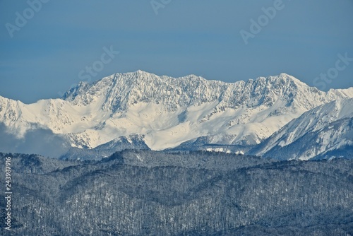 Panorama of snowy mountains. Winter forest and rocky peaks in the snow. Sunny winter day.