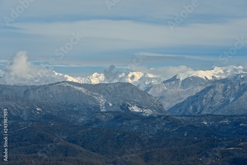 Panorama of snowy mountains. Winter forest and rocky peaks in the snow. Sunny winter day.