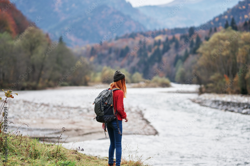 woman with a hiking backpack looks at the nature of the river