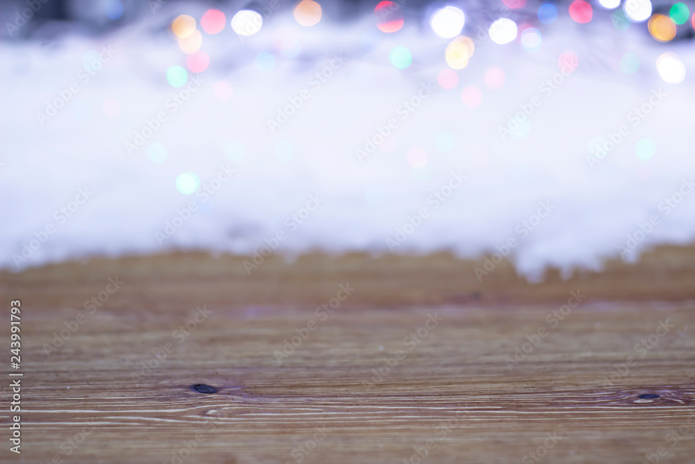 Empty wooden table on a background of snow and bright lights - obrazy, fototapety, plakaty 