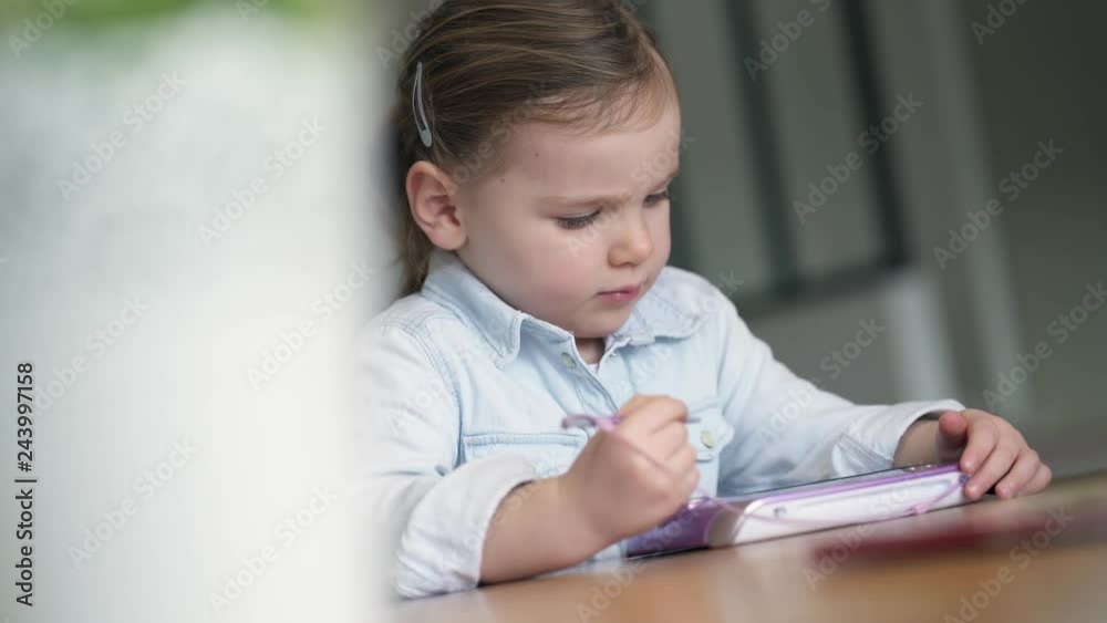 Adorable young girl playing alone on kid's tablet at home Adorable young girl playing alone on kid's tablet at home