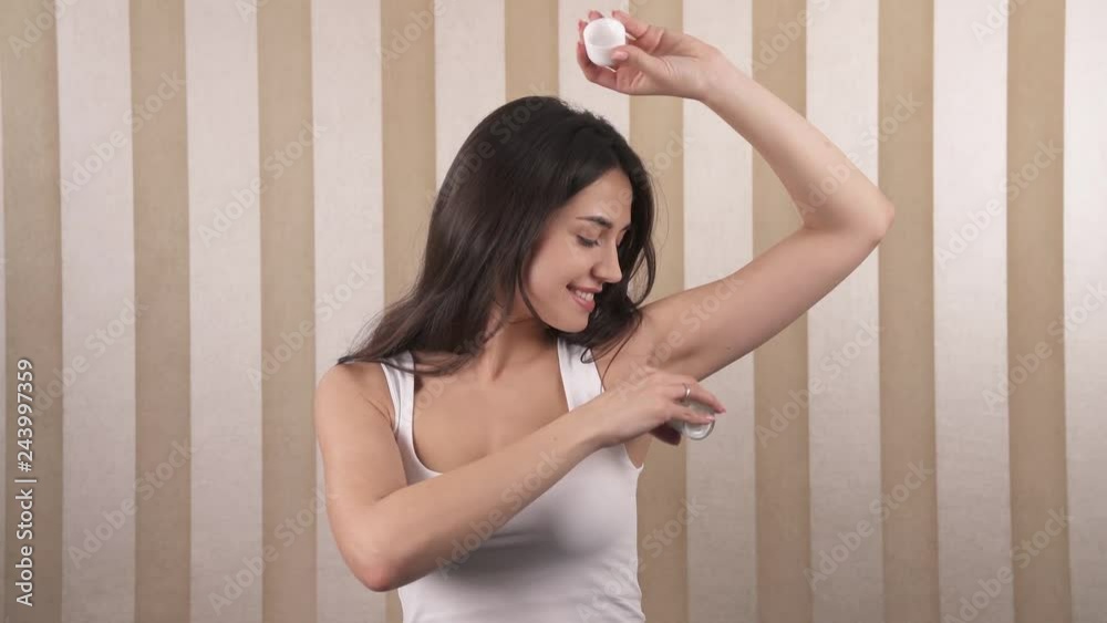 Portrait of a beautiful brown-haired young girl, uses a roll-on deodorant for her left armpit, the right care for an important part of the body. Portrait of a beautiful brown-haired young girl, uses a roll-on deodorant for her left armpit, the right care for an important part of the body.