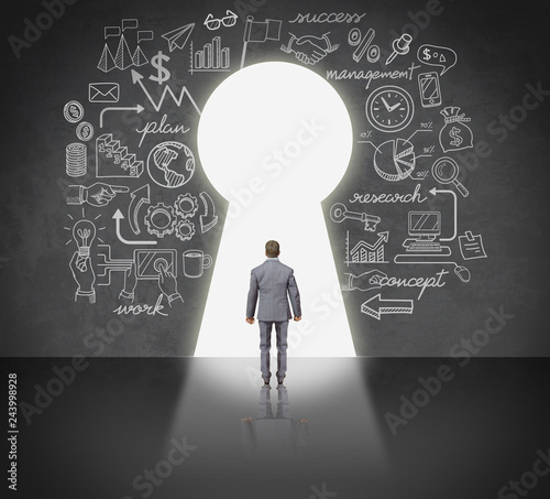 Business man standing front key hole door.