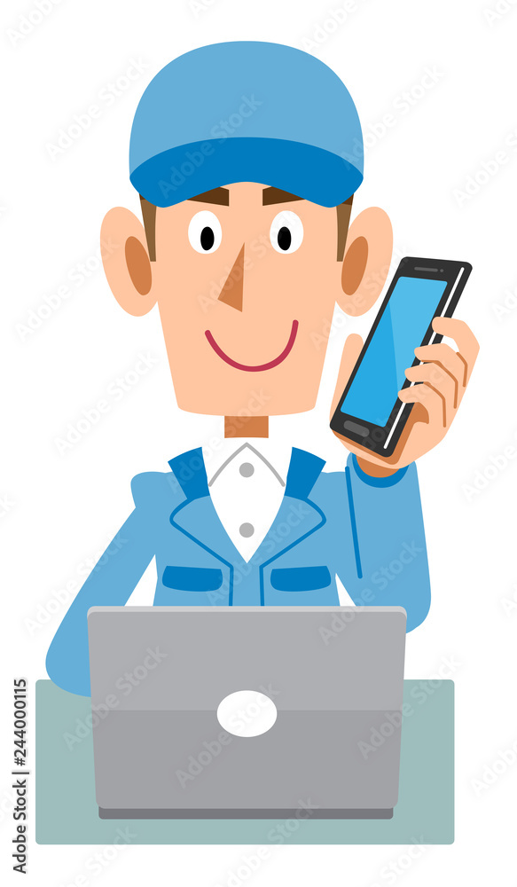携帯電話で会話しながらパソコンを操作する青色の作業服の男性
