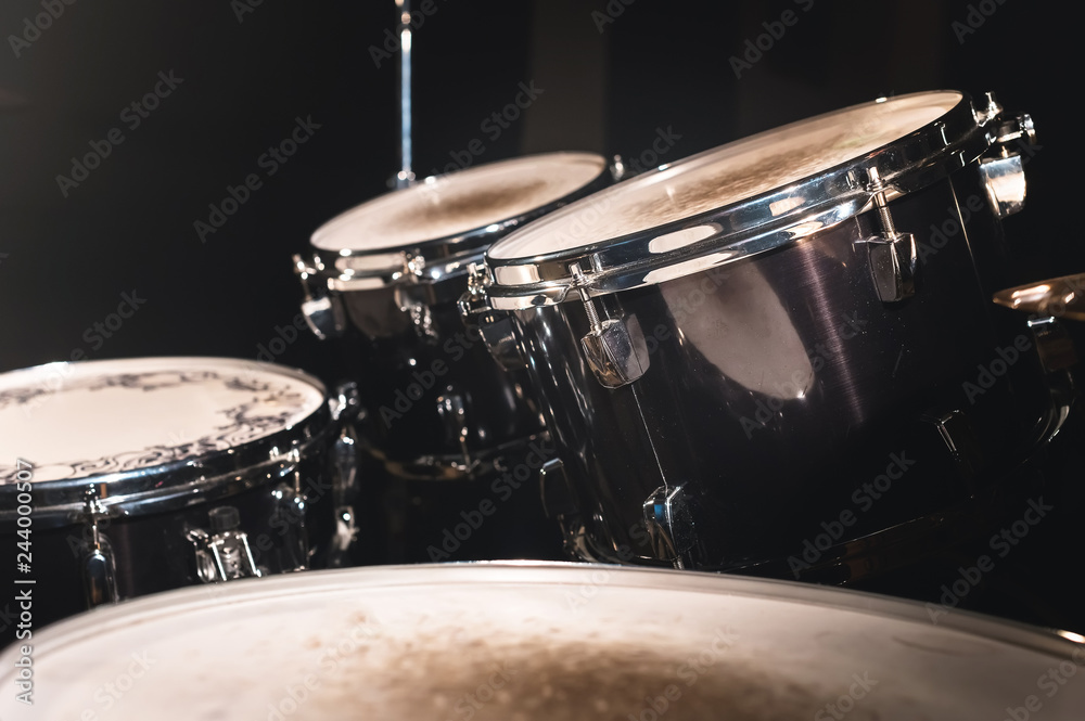 Closeup view of a drum set in a dark studio. Black drum barrels with chrome trim. The concept of live performances Closeup view of a drum set in a dark studio. Black drum barrels with chrome trim. The concept of live performances