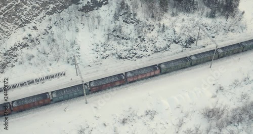 Freight train with coal on Trans Siberian winding two-sided railways near river at winter frozen day in Ural Mountains in Russia - Aerial drone view