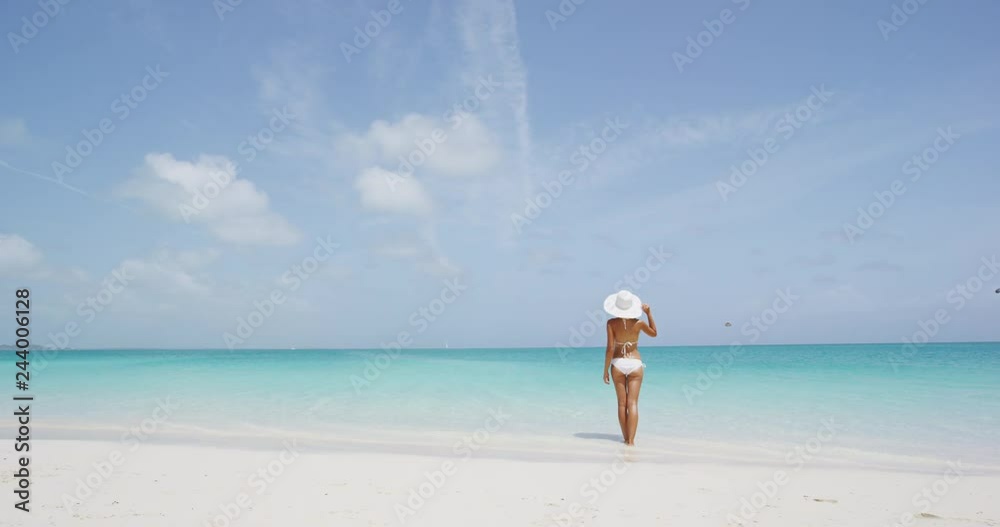 Beach vacation woman in sun happy on summer holidays on tropical beach. Beautiful elegant bikini model wearing beach hat. Beach vacation woman in sun happy on summer holidays on tropical beach. Beautiful elegant bikini model wearing beach hat.