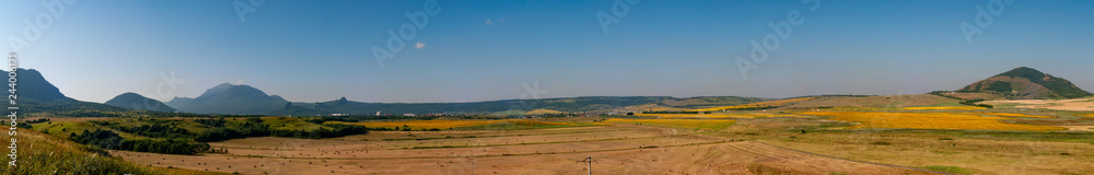 Fields with blooming sunflower. Farm mowing, hay and straw for livestock in winter. Panorama