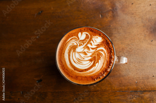 Hot latte art coffee top view on wood table. photo