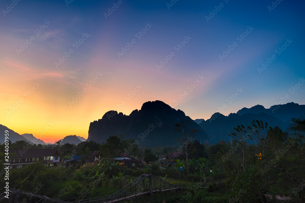 Vang Vieng backpacker travel destination in Laos, Asia. Sunset over scenic cliffs and rock pinnacles, rice paddies valley, stunning landscape.