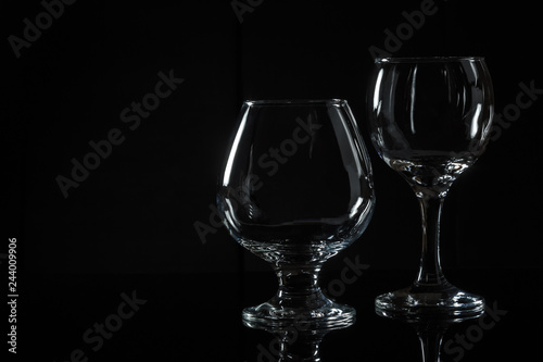 Empty glasses made of transparent glass on a black background. Reflection in a glass base.