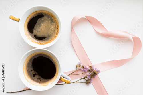 Two cups of coffee in the form of a figure 8. Pink ribbon heart with flowers. Flat lay, top view. Valentines and 8 March Mother Womens Day concept