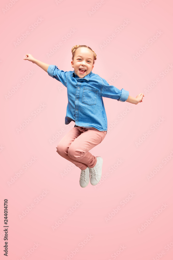 Young happy caucasian teen girl jumping in the air, isolated on pink studio background. Beautiful female full length portrait. Human emotions, facial expression concept.
