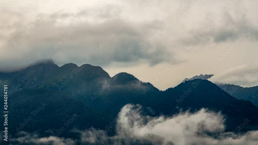 white misty clouds surround dark mountain peaks in the tyrolean alps. The mountains seem mystical in the evening twilight of a dreary rainy day white misty clouds surround dark mountain peaks in the tyrolean alps. The mountains seem mystical in the evening twilight of a dreary rainy day