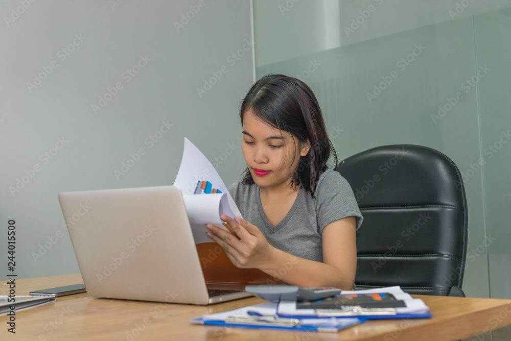 Asian businesswoman reading and checking financial reports in the office Asian businesswoman reading and checking financial reports in the office