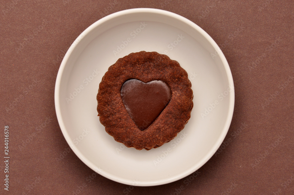 Heart-shaped chocolate chip cookies with toffee, in a white plate, on a brown paper background. Heart-shaped chocolate chip cookies with toffee, in a white plate, on a brown paper background.