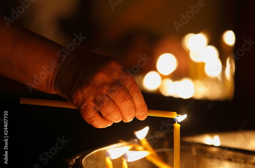 Hand lighting candle in a church