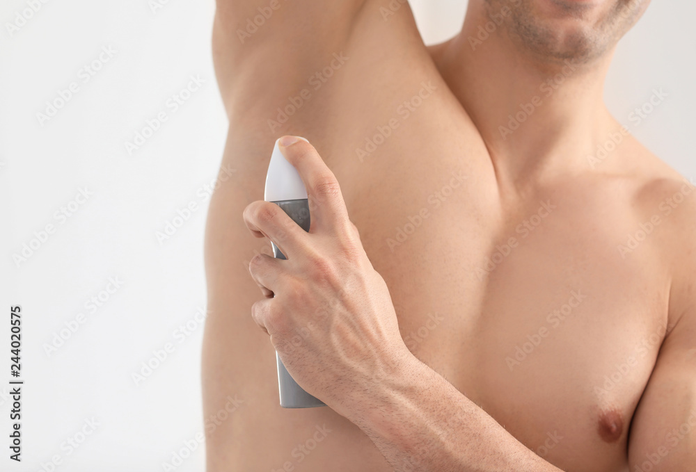 Handsome young man with deodorant in bathroom, closeup