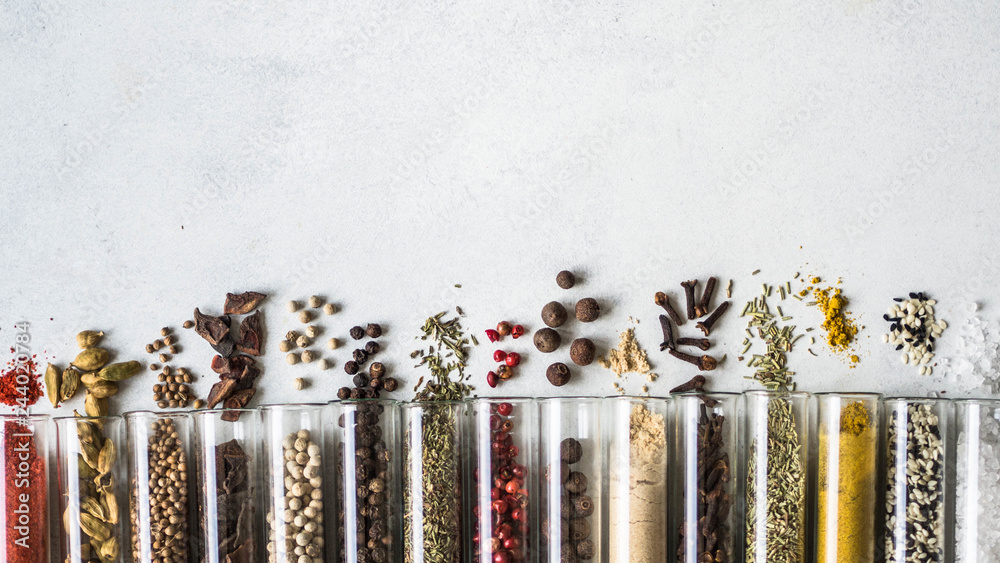 Various dry spices in glass tubes and spilled on gray background. Copy space. top view - obrazy, fototapety, plakaty 