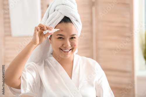 Portrait of young Asian woman with remedy for acne in bathroom