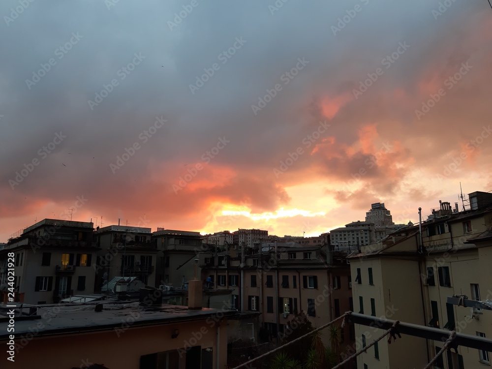 Genova, Italy - 06/17/2018: An amazing sunset over the city of genova in spring days with some clouds and great reflection over the buildings