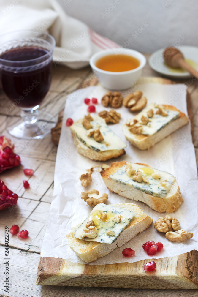 Sandwiches with blue cheese, pomegranate, honey and nuts served with red wine. Rustic style.