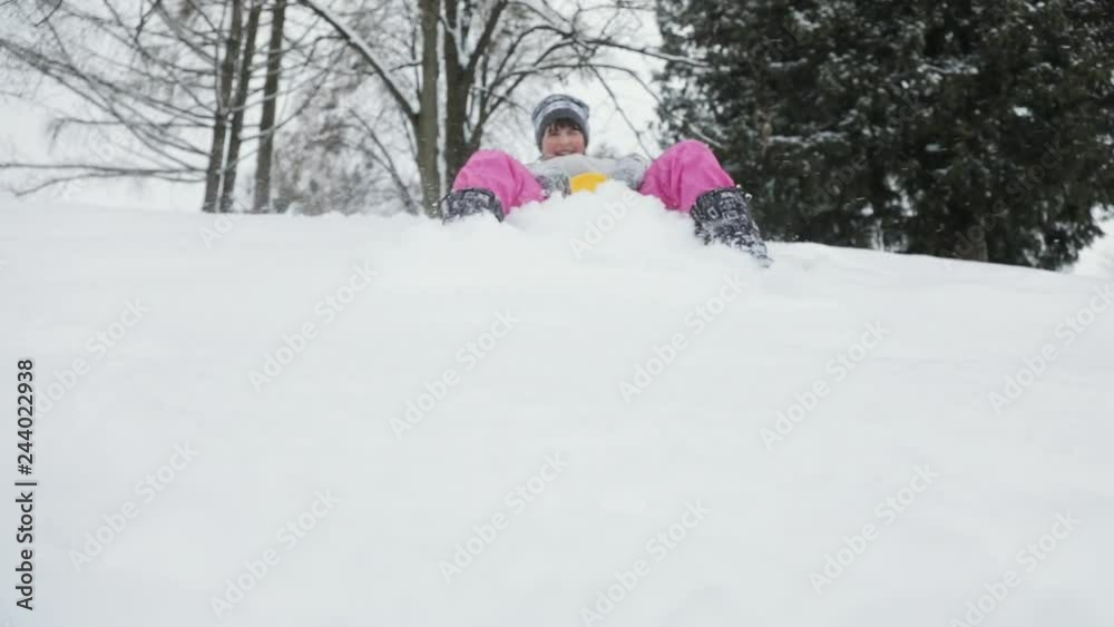 Toddler girl going down a sledge on a snowy hill, winter fun in slow motion Toddler girl going down a sledge on a snowy hill, winter fun in slow motion