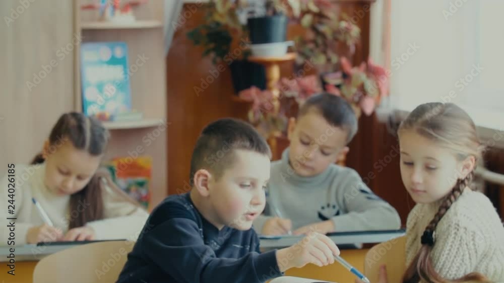 Children write sitting at a desk Children write sitting at a desk