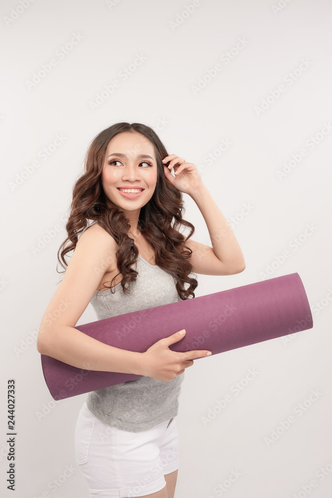 Φωτογραφία Happy sports woman holding yoga mat over gray background