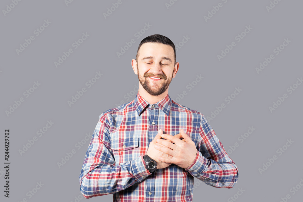 Body language concept. Young handsome man with facial hair posing over gray wall showing emotions. Portrait of masculine bearded male, wearing slim fit checkered shirt. Isolated background, copy space Body language concept. Young handsome man with facial hair posing over gray wall showing emotions. Portrait of masculine bearded male, wearing slim fit checkered shirt. Isolated background, copy space