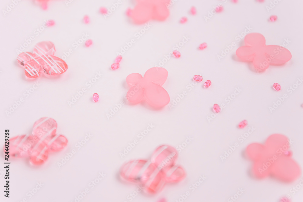 Oval beads and butterfly beads on a pink background. Use as a background, cards. Handicraft and hobby accessories
