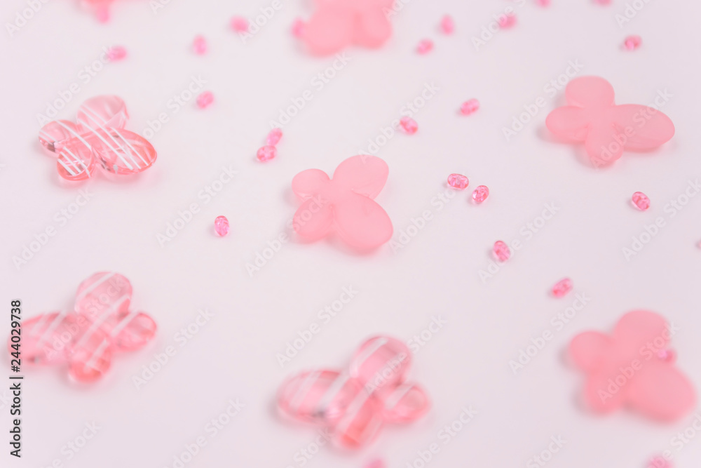 Oval beads and butterfly beads on a pink background. Use as a background, cards. Handicraft and hobby accessories Oval beads and butterfly beads on a pink background. Use as a background, cards. Handicraft and hobby accessories