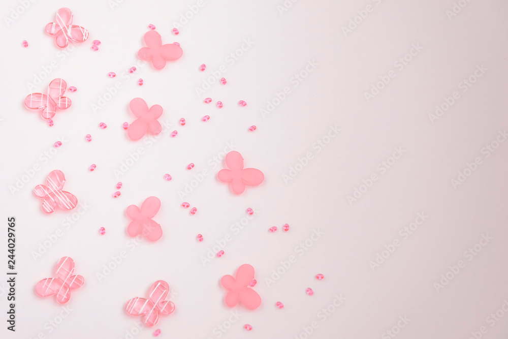 Oval beads and butterfly beads on a pink background. Use as a background, cards. Handicraft and hobby accessories