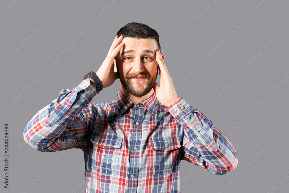 Body language concept. Young handsome man with facial hair posing over gray wall showing emotions. Portrait of masculine bearded male, wearing slim fit checkered shirt. Isolated background, copy space Body language concept. Young handsome man with facial hair posing over gray wall showing emotions. Portrait of masculine bearded male, wearing slim fit checkered shirt. Isolated background, copy space