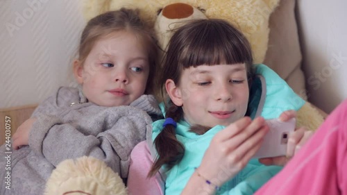 children play online games, two sisters with a smartphone in their hands photo