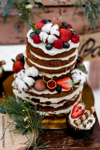 Wedding cake with fruit and an old wooden table with needles of cones and leaves during a wedding ceremony in winter on snow in the middle of a forest covered with fresh snow