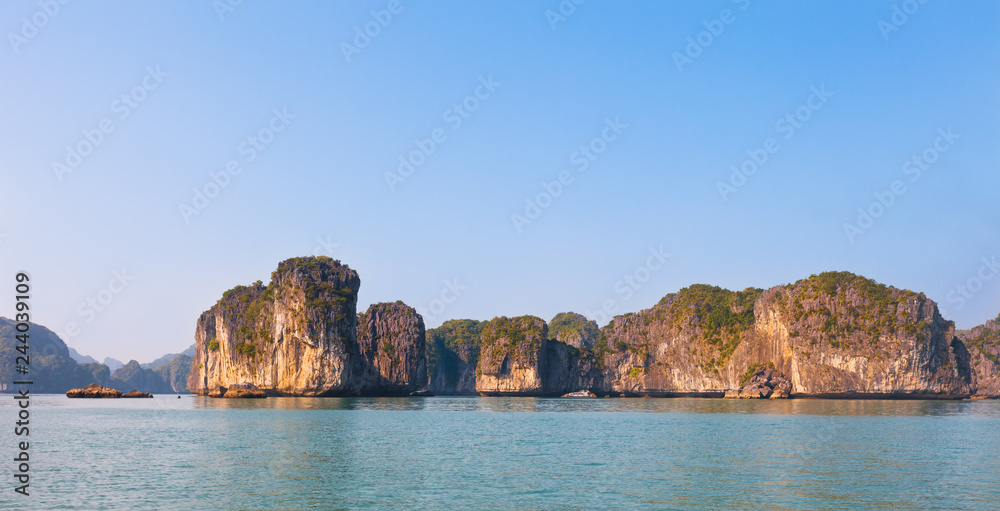 Panoramical landscape of Ha Long Bay in north Vietnam. The bay consists of a dense cluster of some limestone monolithic islands each topped with thick jungle vegetation, rising from the ocean.