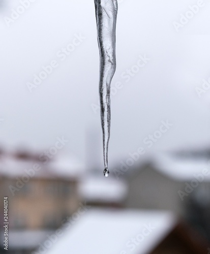 Icicle and falling drop against a gray sky © Pavel Jusif