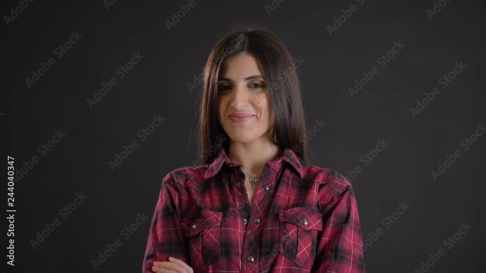 Portrait of caucasian long-haired brunette girl with arms crossed modestly smiling into camera on black background. Portrait of caucasian long-haired brunette girl with arms crossed modestly smiling into camera on black background.